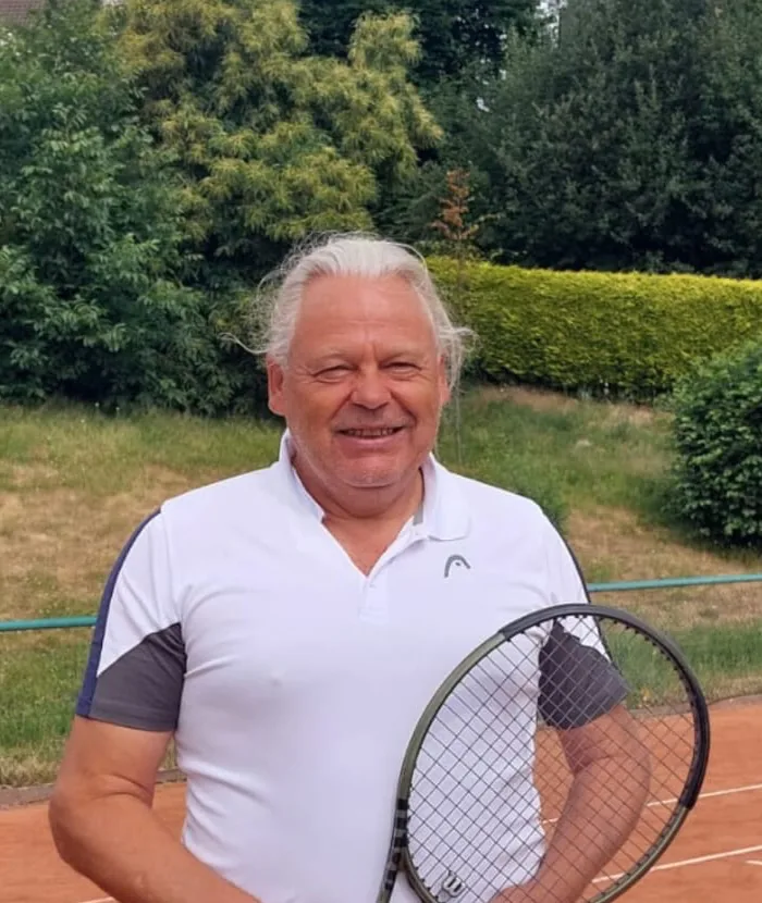 Wolfgang Freres steht vor einem Bällekorb mit Tennisbällen auf einen Asche-Tennisplatz